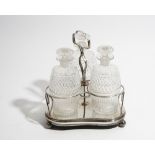 A plated three bottle decanter stand, fitted with three faceted glass decanters and stoppers,