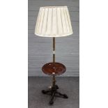 A combination brass and mahogany standard lamp occasional table, on a cast metal paw foot base,