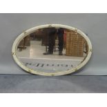 A modern white and parcel gilt decorated oval wall mirror, with bevelled glass,