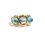 A blue topaz-set dress ring, set with three blue topaz cabochons, in an 18ct gold mount,
