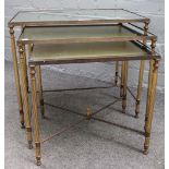 A nest of three mid-20th century mirrored glass and brass occasional tables, on reeded supports,