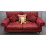 A modern roll arm sofa in patterned red upholstery on turned supports, 193cm wide x 83cm high.