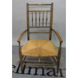 A 19th century stained beech low open armchair with rush seat, 53cm wide x 88cm high.