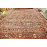 A Hamadan carpet, Persian, the dark indigo field with a bold madder diamond, and spandrels,