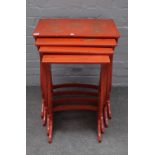 A nest of four 20th century scarlet lacquer occasional tables, on pierced supports,