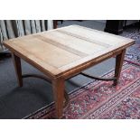 An Arts and Crafts oak draw leaf extending dining table on tapering square supports,