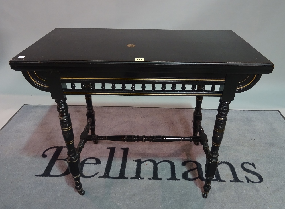 A Victorian ebonised Aesthetic foldover card table, on ring turned supports, 91cm wide x 74cm high.