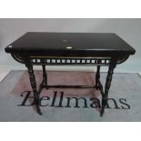A Victorian ebonised Aesthetic foldover card table, on ring turned supports, 91cm wide x 74cm high.