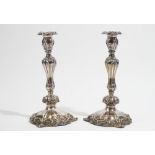 A pair of silver table candlesticks, decorated with foliate scrolls and floral sprays,