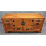 A 19th century Chinese elm low cabinet, with a pair of cupboards and six drawers, on bracket feet,