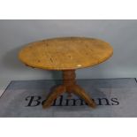 An early 20th century pine circular dining table on turned column and three downswept supports,