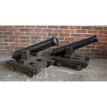A pair of 20th century black painted imitation cannons, mounted on dollys, length of cannons 82cm.