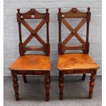 A pair of Gothic Revival oak and walnut hall chairs, with X-frame backs, 46cm wide x 101cm high.