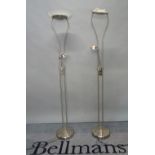 A pair of modern chrome uplighters of tubular form with a mid-tier adjustable reading light and