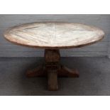 A pine circular table with distressed finish, on square baluster supports,