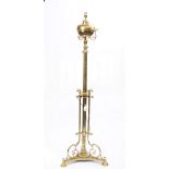 A Victorian brass height adjustable standard lamp (converted), on a scroll frame and three pad feet,