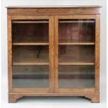 An oak dwarf bookcase, 20th century, enclosed by a pair of glazed doors,