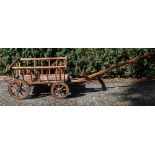 A vintage wooden pull-along cart, with spindle filled sides and rubber mounted wooden wheels,