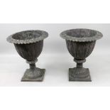 A pair of black painted cast iron terrace urns, in classical style, with stylised leaf rims,