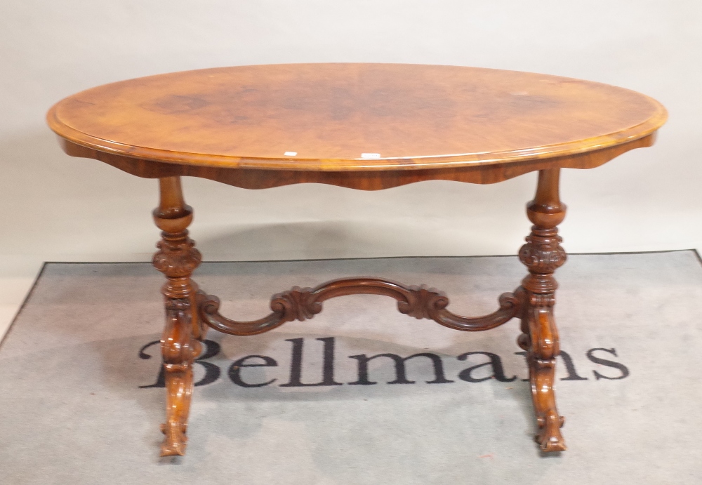 A Victorian style walnut oval centre table on four outswept suports,