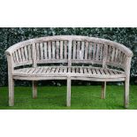 A teak semi-elliptic garden bench of slatted construction on block supports,