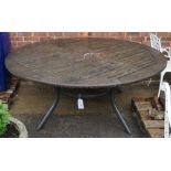 A large slatted circular garden table on four splayed metal supports, 180cm diameter x 75cm high.