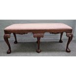 A George III style mahogany rectangular footstool, with carved frieze on six claw and ball supports,