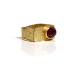 An 18ct gold ring of rectangular form, mounted with an oval cabochon pink tourmaline,