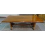 A modern hardwood rectangular dining table on carved trestle supports united by stretcher,