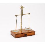 A pharmacist’s Victorian walnut and brass set of beam scales, the drawer fitted with the weights,