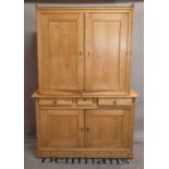 An early 20th century pine housekeepers cabinet with two pairs of cupboard doors divided by three