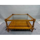 A modern stained beech and walnut two tier square coffee table with glass top,