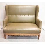 An early 20th century oak framed wingback two seater sofa on reeded tapering supports,