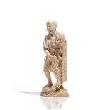 A Japanese ivory okimono of a fisherman, Meiji period, carved standing on rocks holding a net,