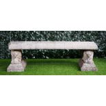 A reconstituted stone curved garden bench, on a pair of recumbent lion supports,