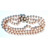 A three row choker of coral beads, on a gold and coral bead cluster clasp,