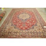 A machine made carpet of Persian design, the red field with a round medallion, 345cm x 250cm.