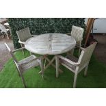 A teak circular garden table on folding X frame base,