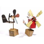 Two primitive/folk art whirlygigs both modelled as a person cranking a windmill, approx 35cm high.