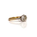 An 18ct gold ring, claw set with a circular cut diamond between platinum shoulders,