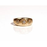 An 18ct gold and diamond set three stone ring, star gypsy set with a row of cushion shaped diamonds,