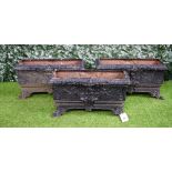 A set of three black painted cast iron rectangular planters with relief floral cast decoration,