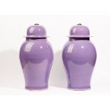 A pair of modern baluster vases and covers, with a lilac ground and having brass ring handles,