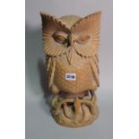 A 20th century carved hardwood large figure of an owl upon a snake, 46cm tall.