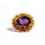 A 9ct gold brooch, claw set with an oval cut amethyst within a two tier radiating surround,