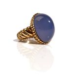 A gold ring, mounted with an oval cabochon blue stained chalcedony,