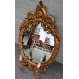 A Victorian gilt framed girandole wall mirror with opposing 'C' scroll crest above the oval mirror