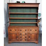 A late George III oak dresser, the enclosed three tier plate rack, over six frieze drawers,