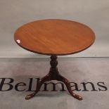 A George III mahogany tripod table with turned column on three downswept supports,