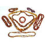 A single row necklace of graduated oval varicoloured translucent amber beads, on a gold clasp,